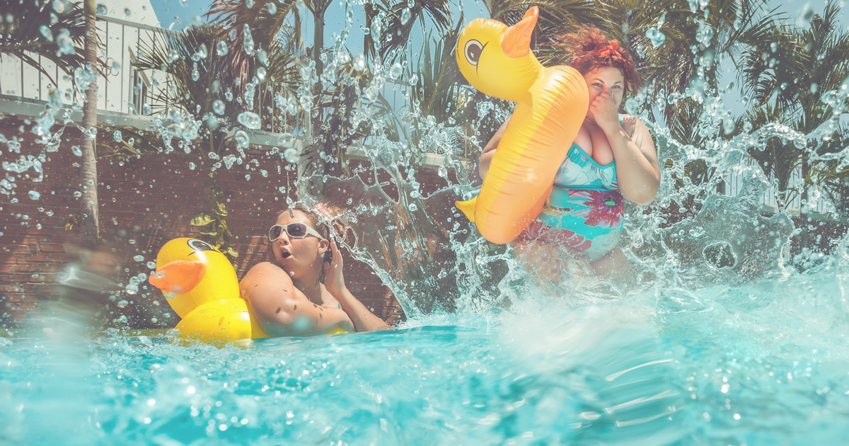 Two plus size women jumping into a pool