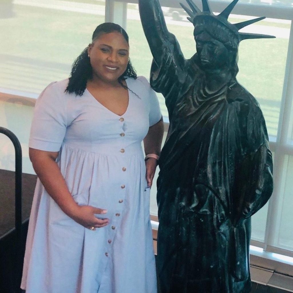 black plus size pregnant woman standing next to statue 