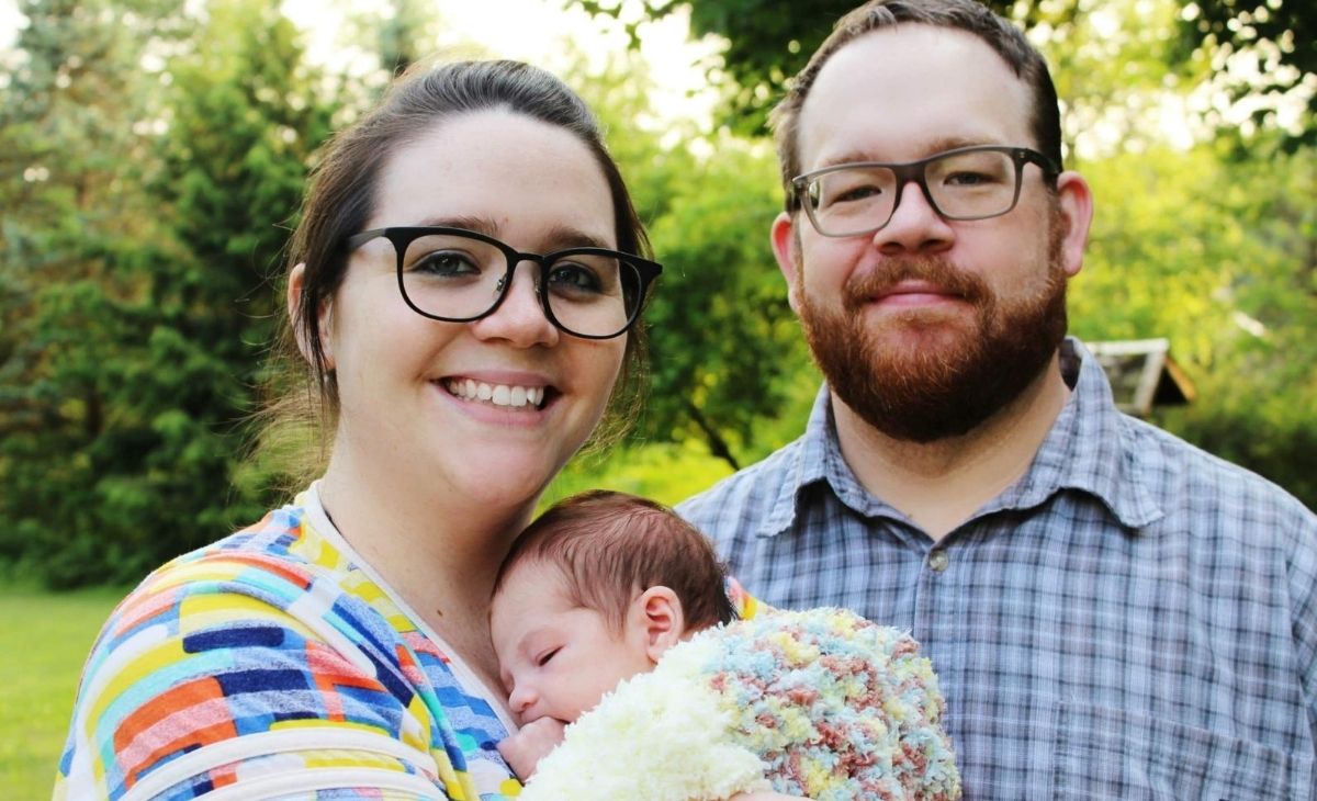 plus size mom holding baby with husband