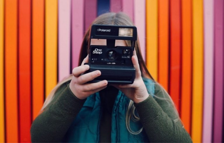 woman holding camera with colorful background