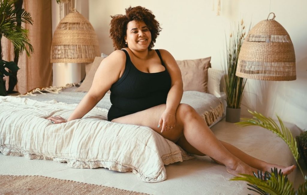 plus size woman sitting on a bed 