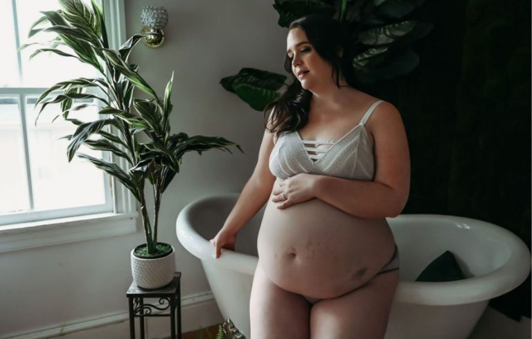 photo of a plus size woman holding her belly celebrating a Donor Egg Success Story