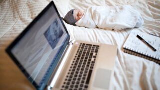 baby and laptop on bed
