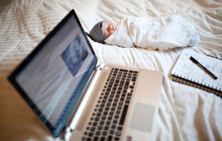 baby and laptop on bed