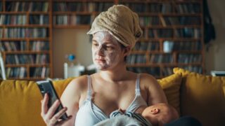 mom during postpartum breastfeeding wearing a face mask and holding phone