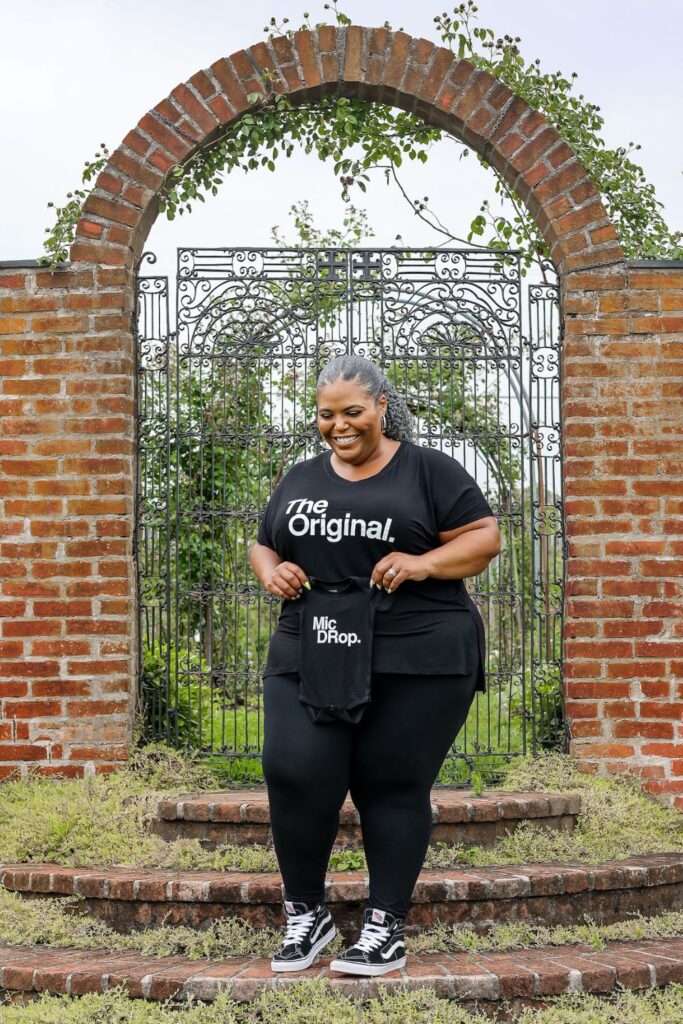 plus size pregnant woman holding a baby onesie for a plus size pregnancy announcement 