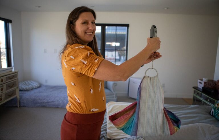 home birth midwife weighing baby and smiling at camera