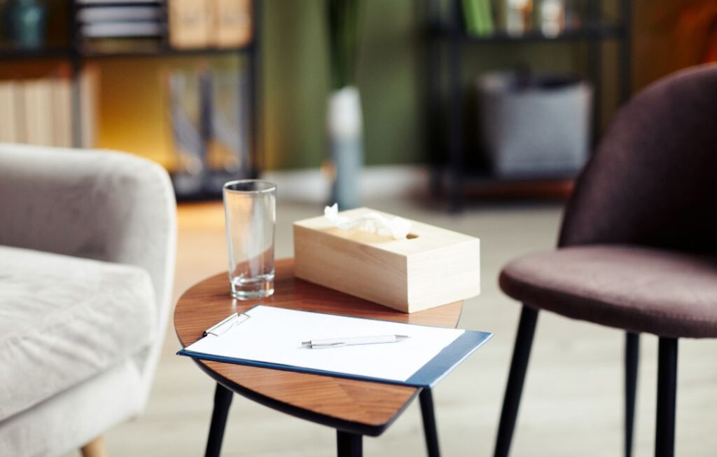 therapy office with couch, chair, tissues and notepad